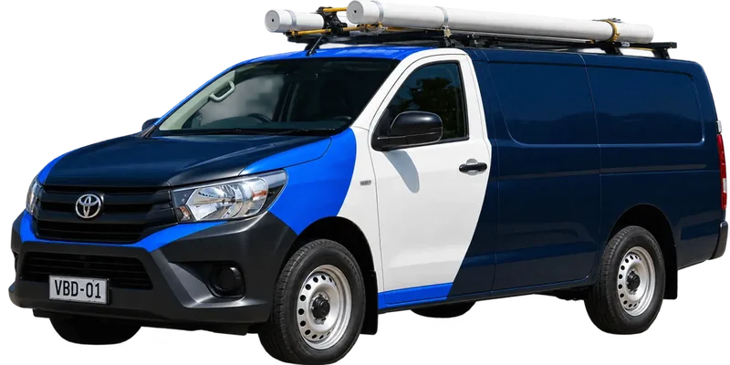 A licensed Gladesville plumbing van loaded with pipe on the roof rack